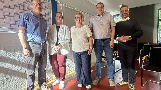 5 Personen stehen vor einer Wand